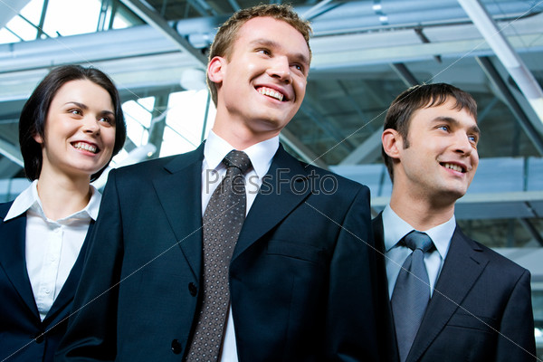 Portrait of strong business team standing next to each other and looking aside in the modern building, stock photo