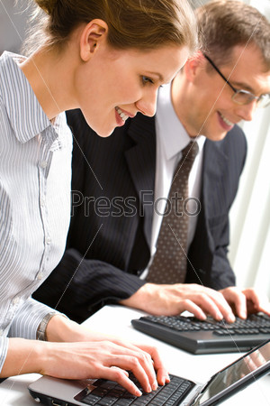 Row of business people typing something over laptop and computer