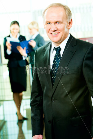 Portrait of skilful manager standing in the office on the background of business women