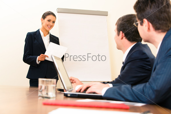 Portrait of smiling manager standing at whiteboard and looking at businessmen