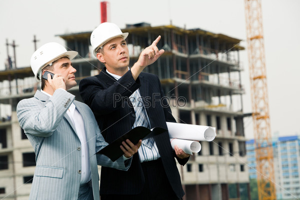 Photo of serious employee pointing at something with calling foreman standing near by