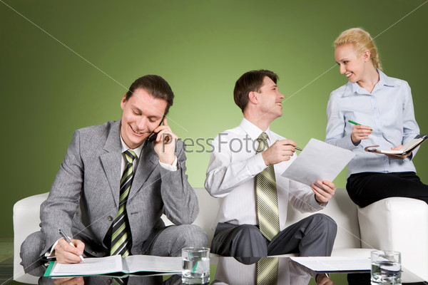Image of smiling businessman calling by phone while his partners discussing new plans in office