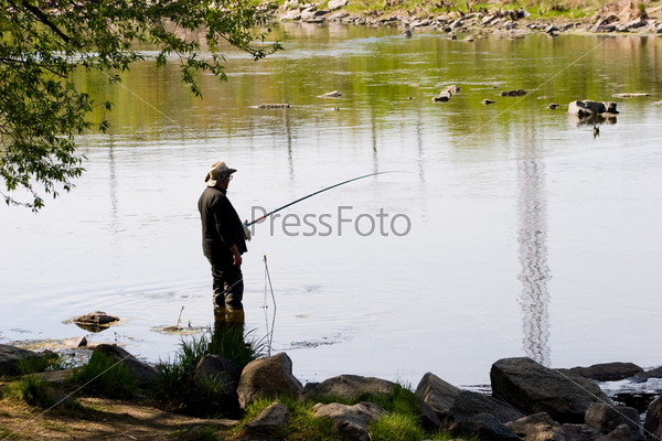 Photo of a fisher angling by the river in windless weather