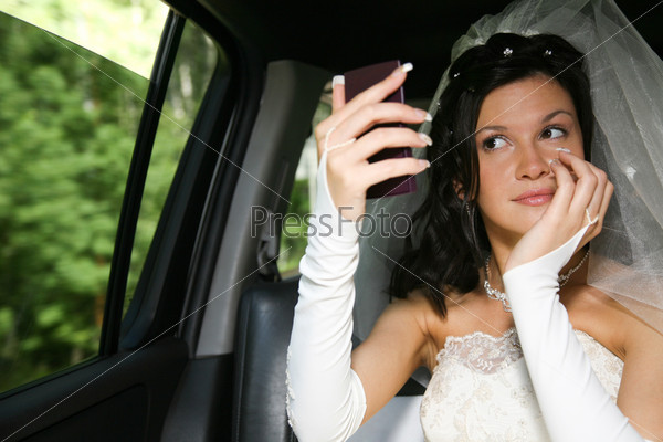 Photo of happy woman in wedding dress looking at the mirror