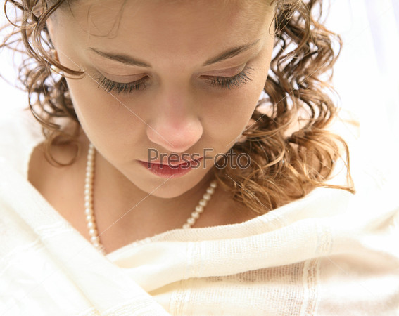 Close-up of bride’s face looking down over white background