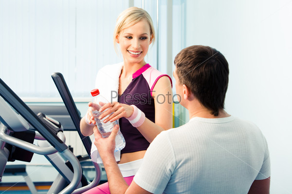 Image of man giving the bottle of water to woman in the health club