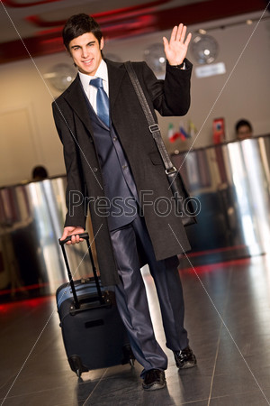 Portrait of handsome businessman walking down the airport and saying goodbye