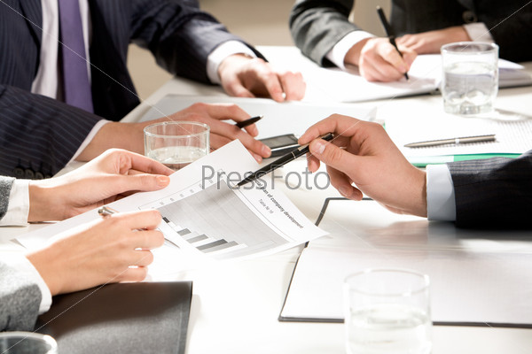 Photo of people hands during teamwork at meeting on table working with papers