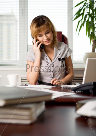Portrait of executive woman talking on the phone with client of corporation where she works
