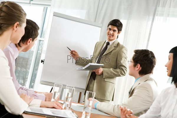 Photo of attentive business partners looking at successful entrepreneur pointing at whiteboard in office