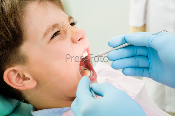 Close-up of little boy opening mouth for dental checkup in stomatological office