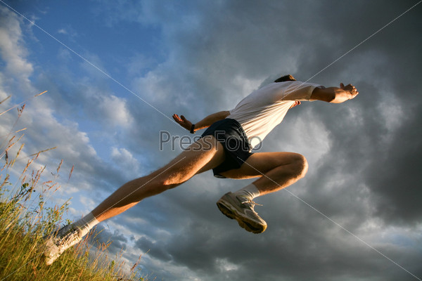 View from below: athlete raising leg and hand