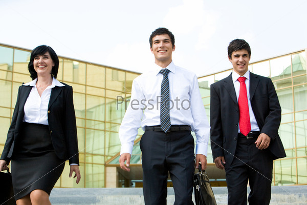 Portrait of confident business people walking outdoors and looking forwards
