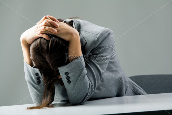 Photo of depressed female sitting at workplace and grieving