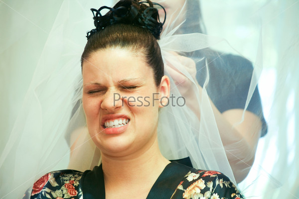 Face of young woman expressing pain while her hair is being done for wedding