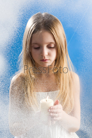 Photo of peaceful girl with candle standing behind snowy window