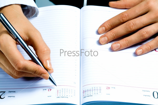 Image of writing instrument in human hands over notepad