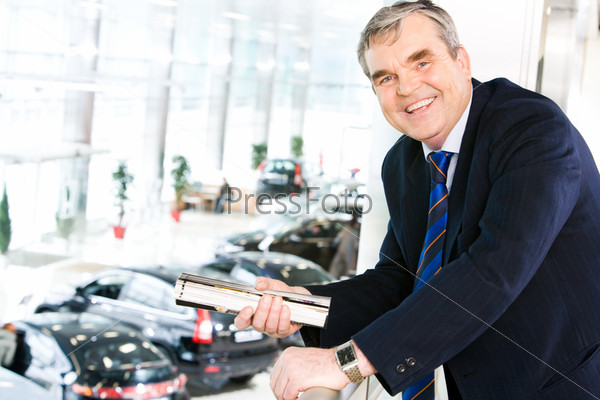 Portrait of mature leader looking at camera joyfully in the car center