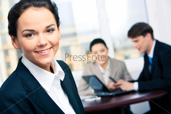 Portrait of beautiful secretary in suit looking at camera in a working environment