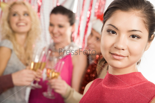 Face of pretty girl looking at camera with smile on background of her friends partying