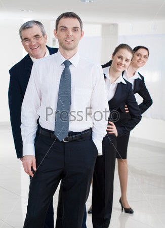 Portrait of successful businessman looking at camera on background of several co-workers