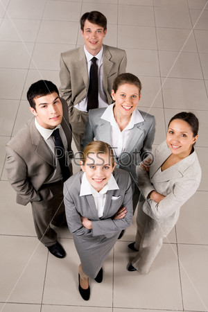 Portrait of confident business group standing on the floor and looking at camera with smiles