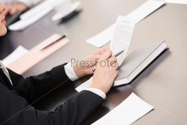 Close-up of businesswoman holding document and reading it at workplace