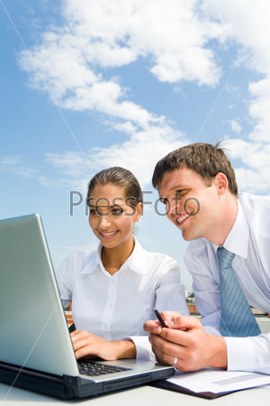 Portrait of successful partners working with laptop in the city under blue sky