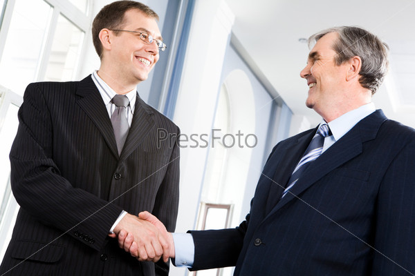 Portrait of businessmen shaking hands greeting each other in the corridor