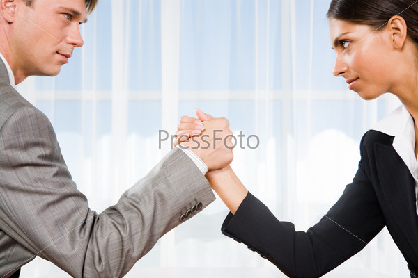 Portrait of business competitors doing arm wrestling and looking into each otherâ??s eyes
