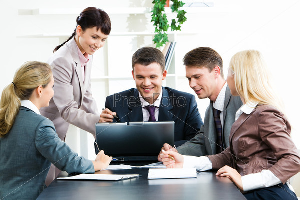 Photo of confident business people looking at laptop monitor while woman pointing at it with two females sitting in front