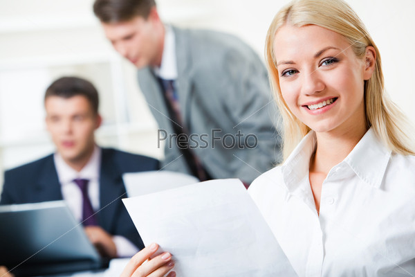 Portrait of pretty young agent with paper on the background of businessmen