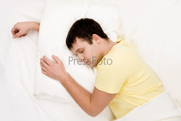 Image of man sleeping with one arm under pillow while the other one being bent