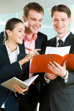 Vertical image of three business partners standing and discussing documents