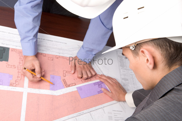 Above view of engineers over blueprints during discussion