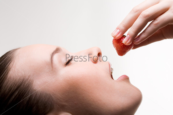 Image of pretty girl with open mouth and ripe strawberry in hand, stock photo
