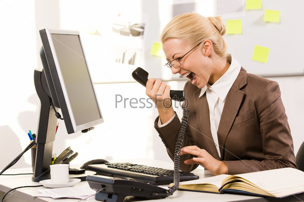 Photo of aggressive secretary shouting into phone receiver while sitting in office