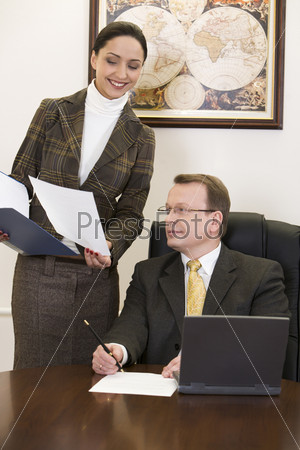 Beautiful woman is showing an official record to the sitting man in the suit