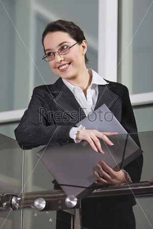 Successful businesswoman with the paper-case in her hand near the glassy railing