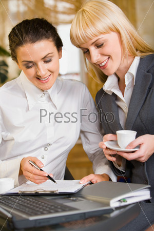 Portrait of two confident women discussing a business questions in a cafe