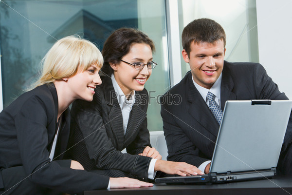 Group of three business people looking at monitor, stock photo