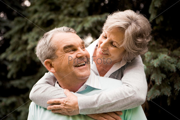 Portrait of senior female embracing her husband while he laughing and looking at her