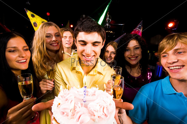 Portrait of smart guy with birthday cake surrounded by friends with champagne