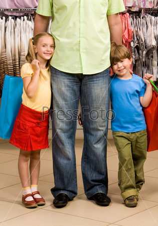Portrait of happy girl and boy embracing their father in the mall