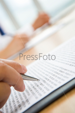 Vertical image of human hand holding pen and making notes