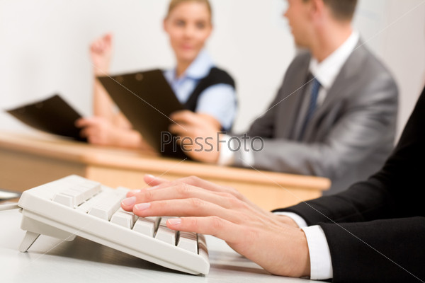 Photo of female?s hands pushing buttons of computer keyboard with communicating partners on background