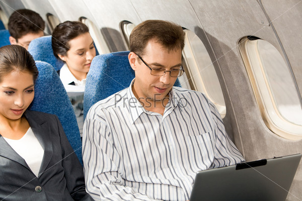 Photo of pretty woman with handsome man typing next to her in airplane