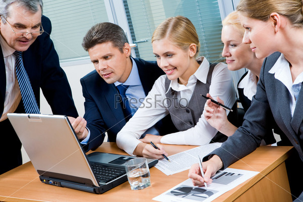 Portrait of executive employees looking at laptop monitor in office