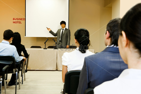 Image of confident businessman explaining something on whiteboard during conference