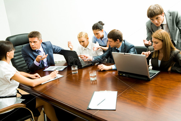Image of company of successful partners communicating at meeting